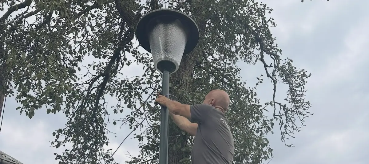 Monteur bevestigt een camera aan een bestaande lantaarnpaal in Blaricum