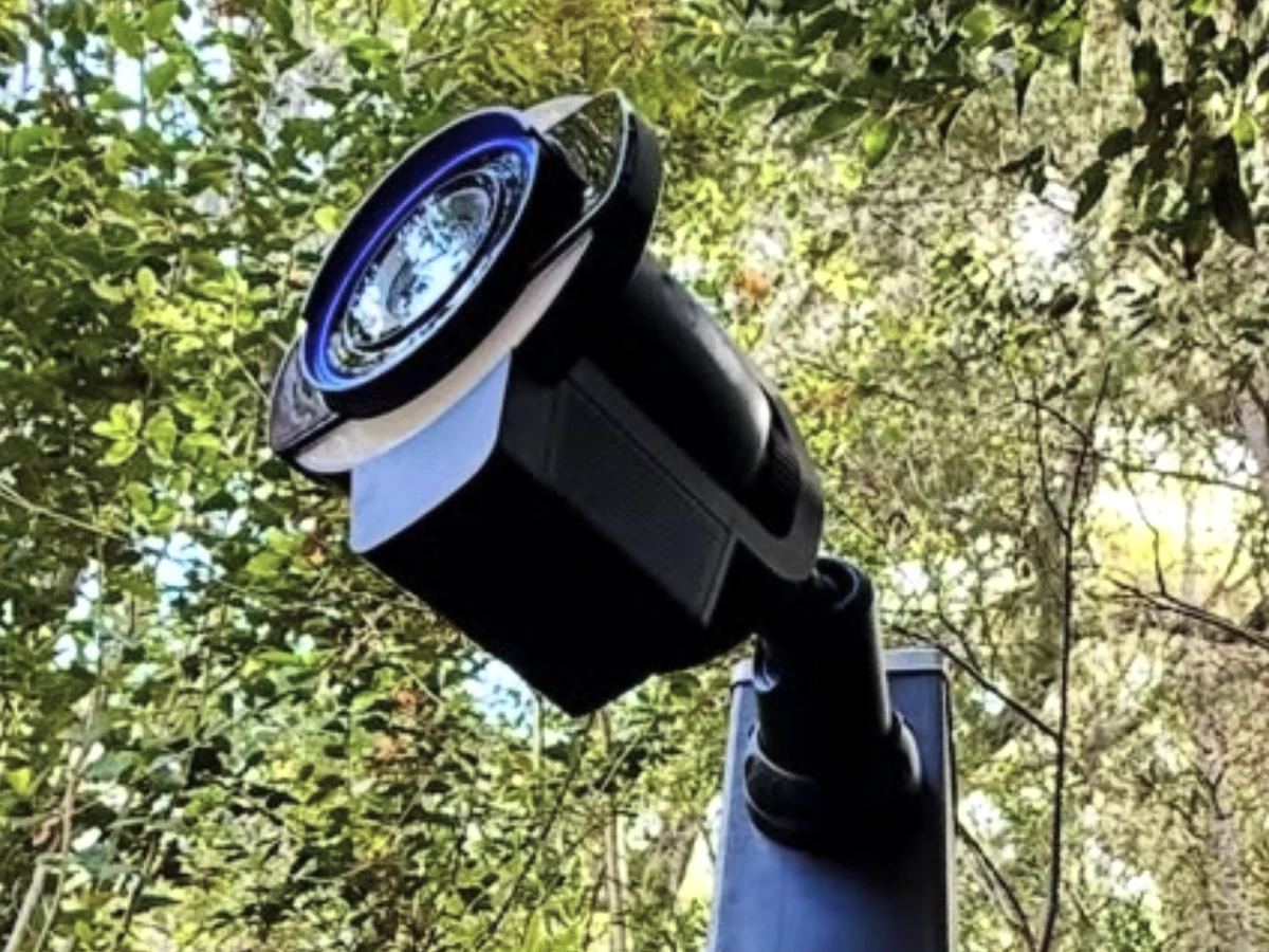 Camera met ingebouwde schijnwerper op een paal in de tuin