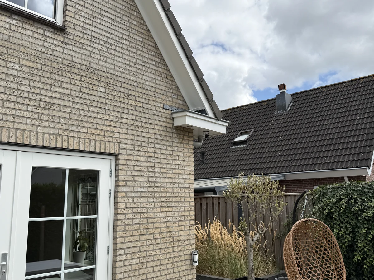 Camera onder het dakoverstek en een buitenmelder naast de tuindeur