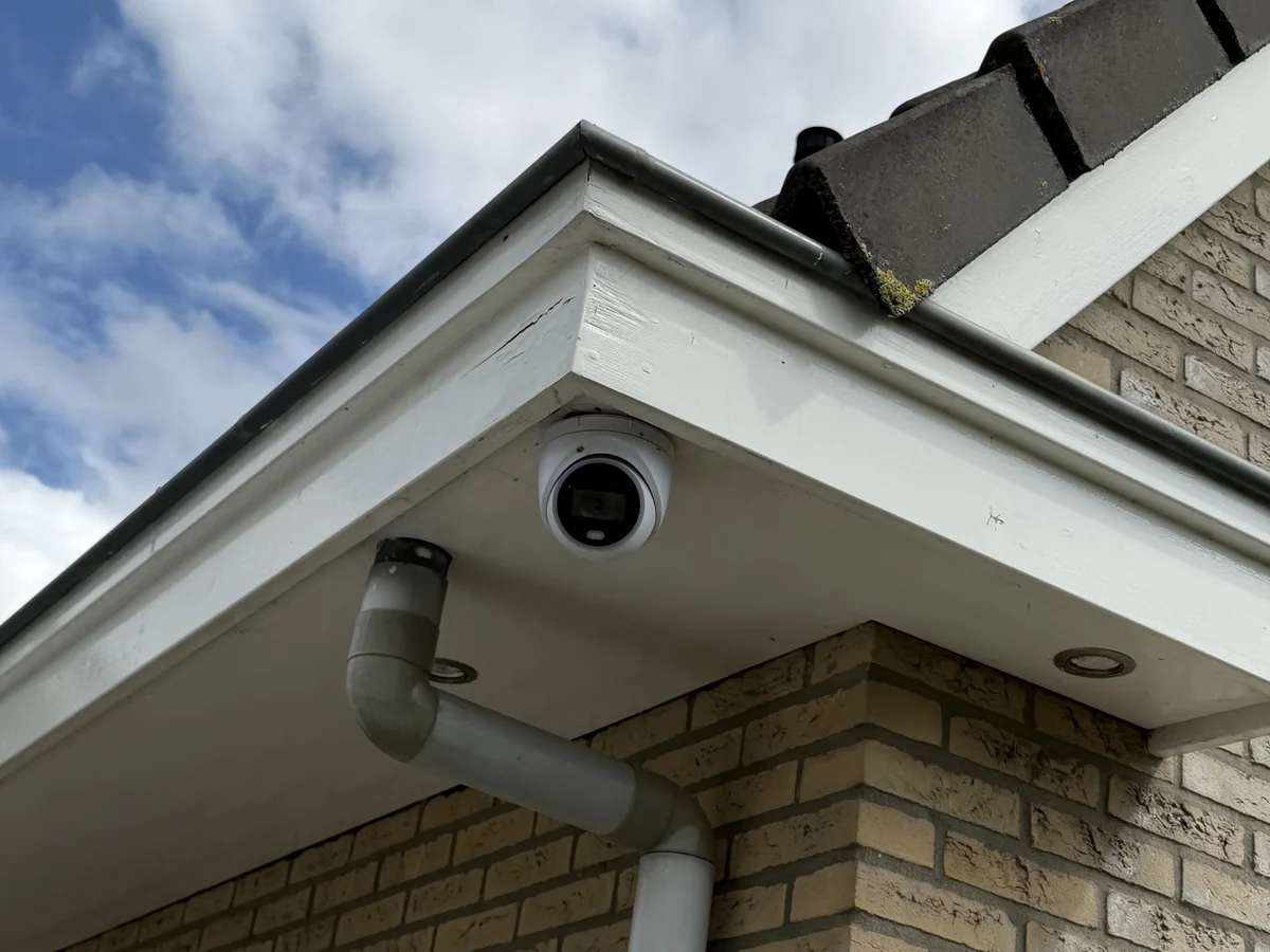 Witte dome-camera onder het overstek van een vrijstaande woning
