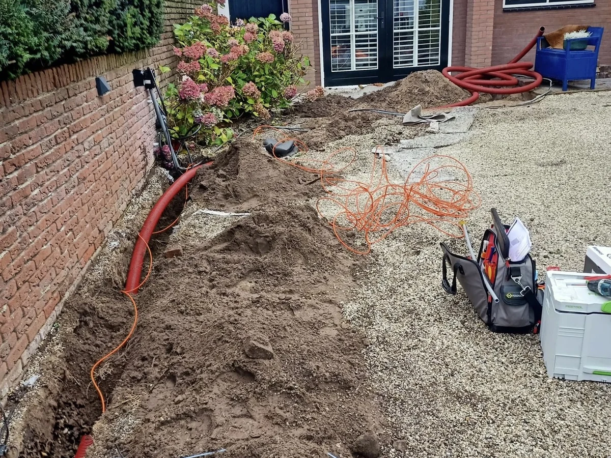 Kabeltracé door de tuin, met eigen grondwerk langs de tuinmuur