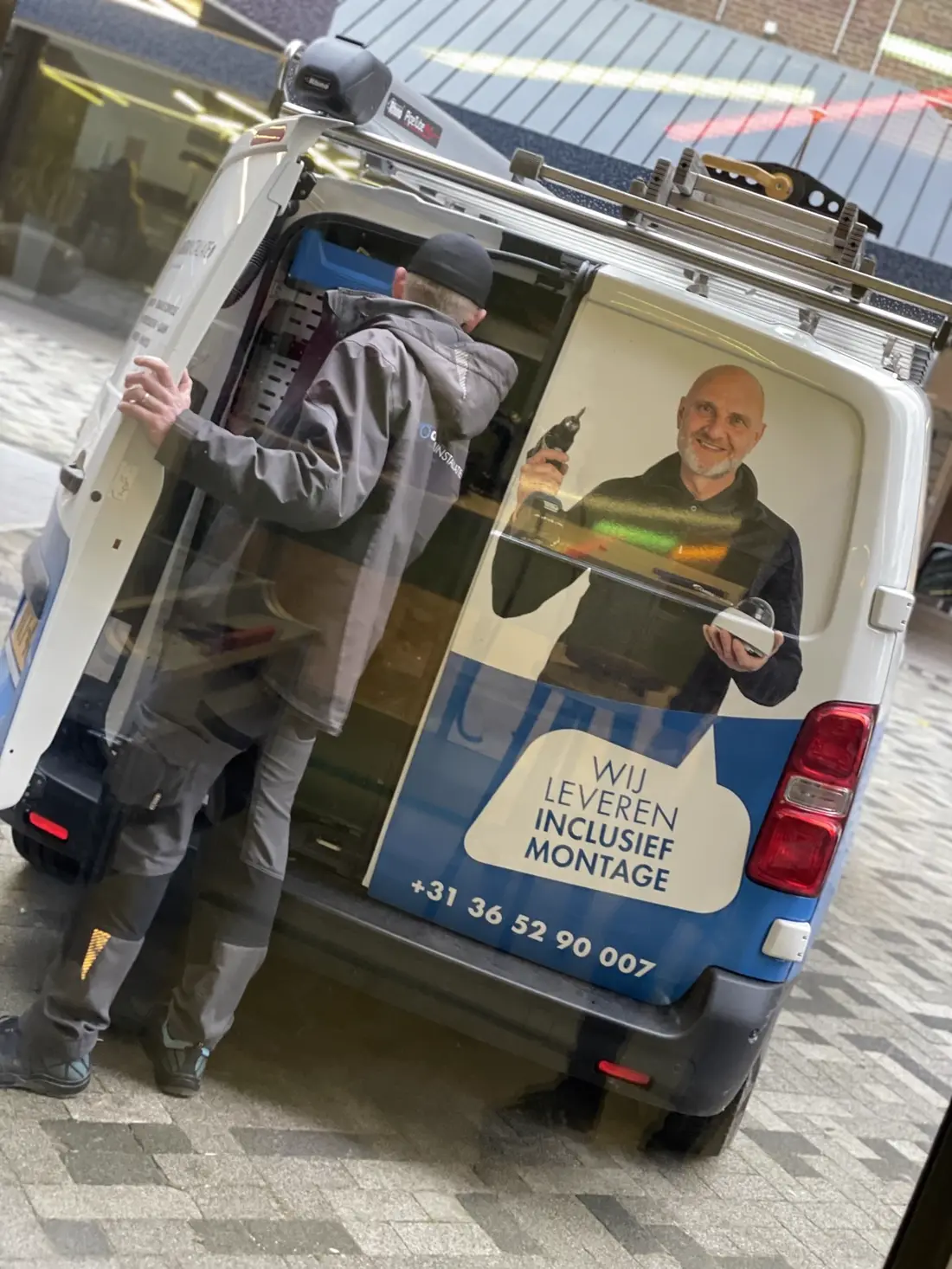 Monteur pakt materiaal uit de eigen bus