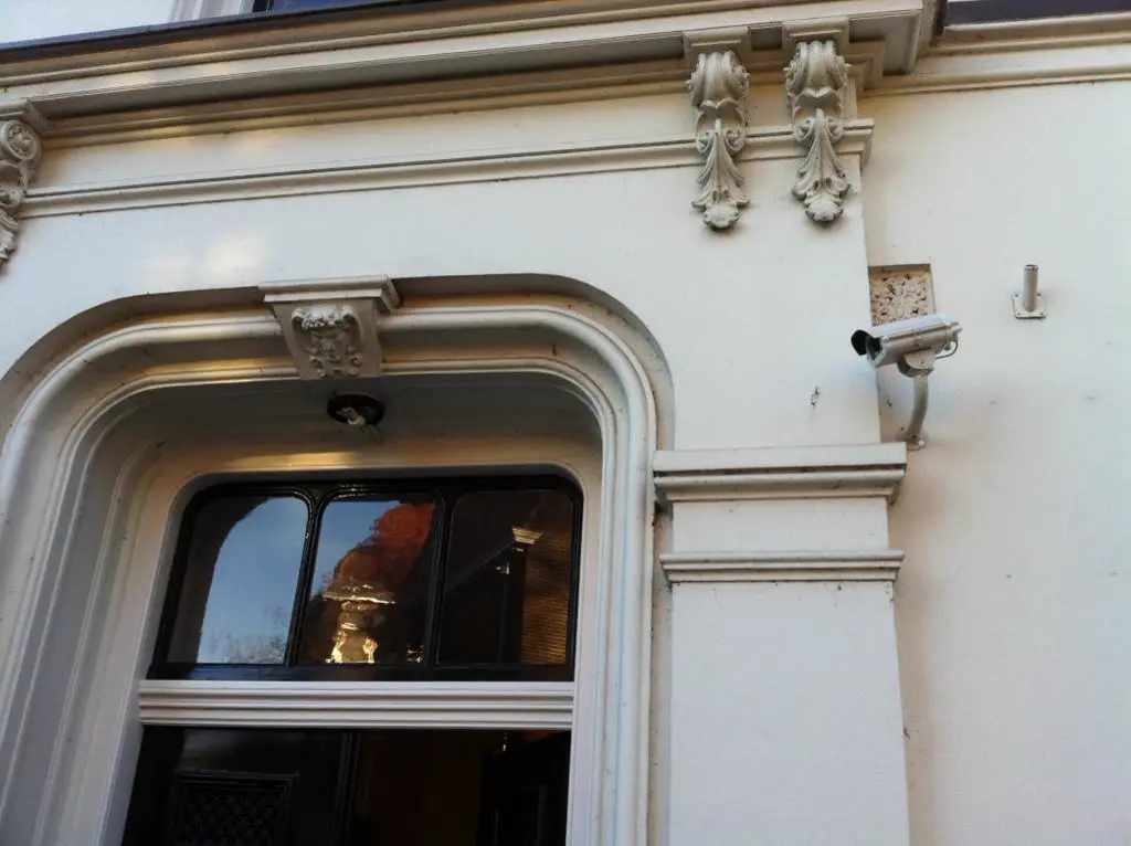 Witte nachtzichtcamera op de sierlijst van een monumentale gevel
