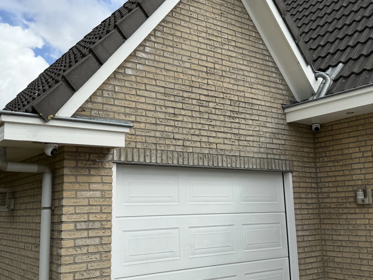 Twee camera&rsquo;s onder het dakoverstek bij de garage, met zicht op oprit en zijkant