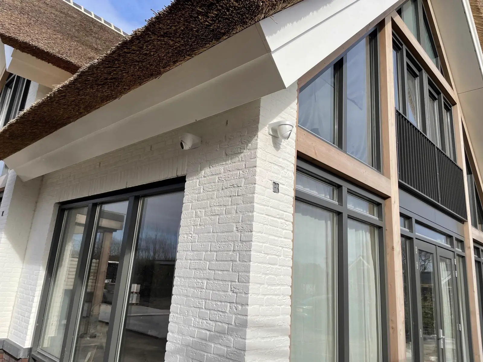 Villa met rieten kap, twee camera&rsquo;s netjes onder de dakrand