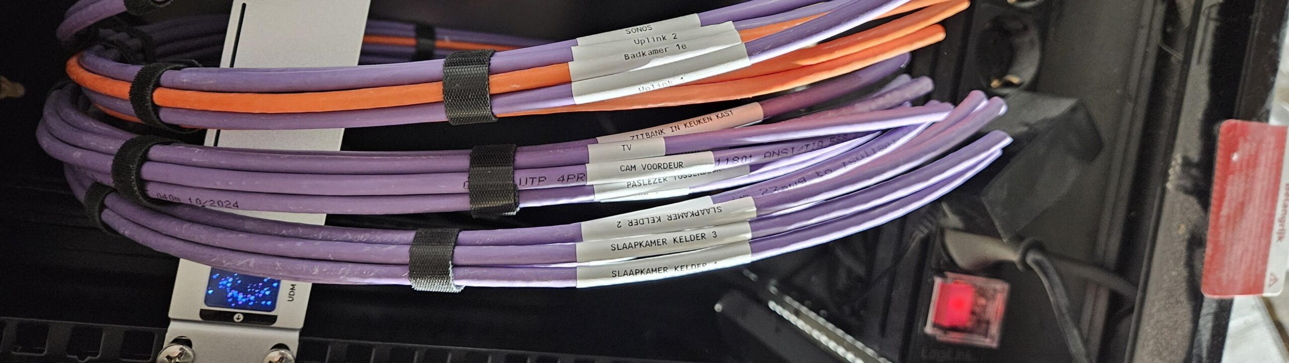 Paarse en oranje netwerkkabels met witte labels zoals Sonos, Badkamer 1e, Cam voordeur en TV