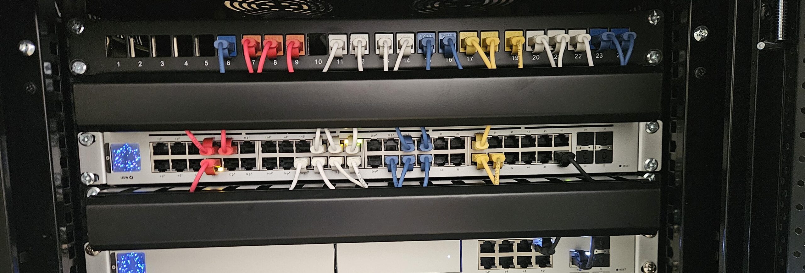 Close-up van een patchpaneel en switch met rode, witte, blauwe en gele kabels