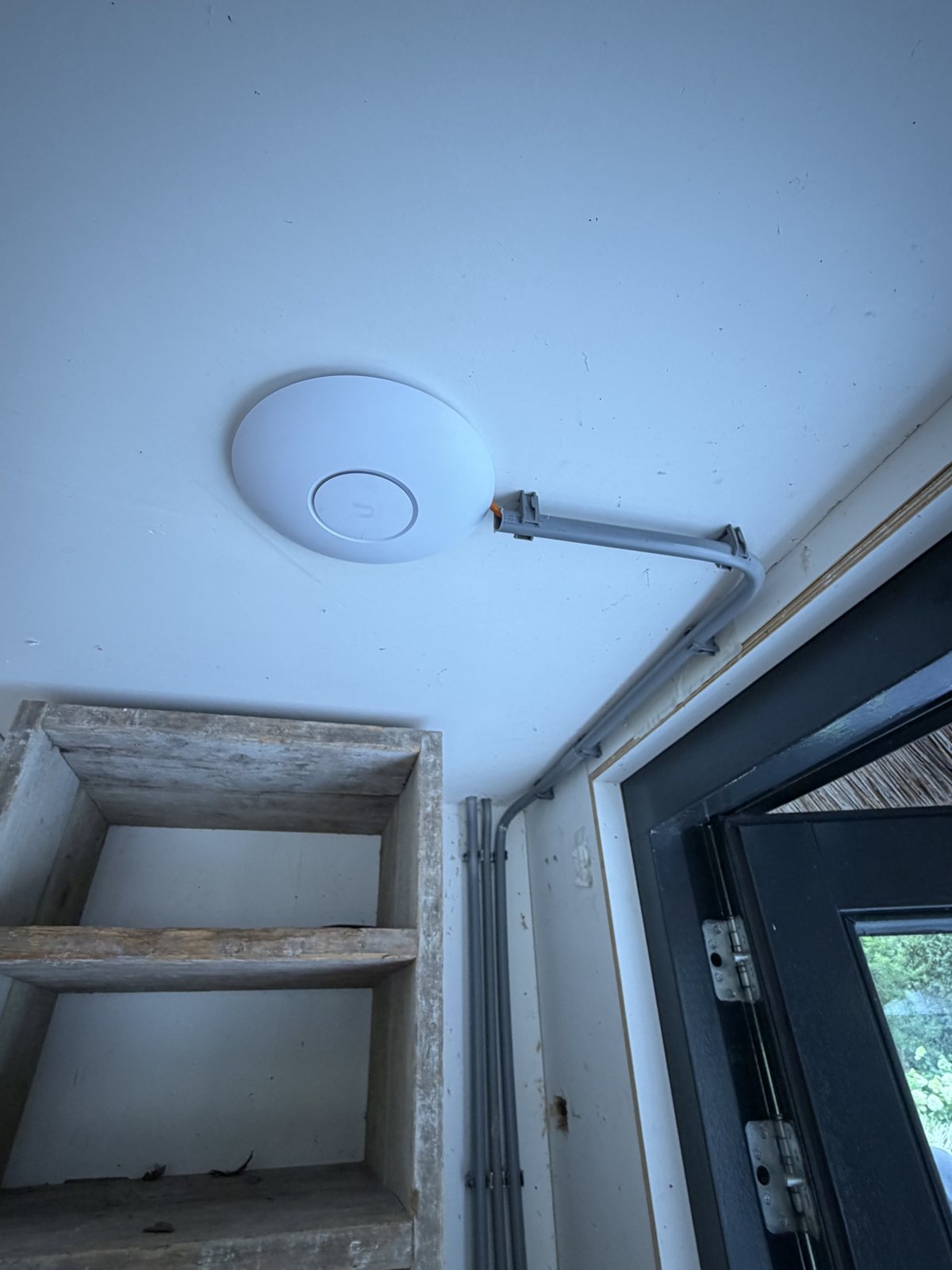Wifi-zender aan het plafond van een villa in Blaricum, de kabel in een strakke grijze goot langs de muur