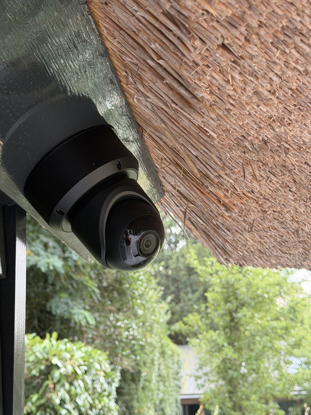 Zwarte camera tegen het houtwerk direct onder de rand van het rieten dak